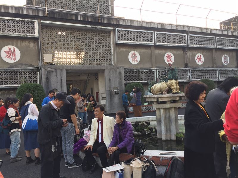 受難者前輩陳深景先生(著白色西裝)於獬豸水池前接受台灣新生報記者王先國採訪