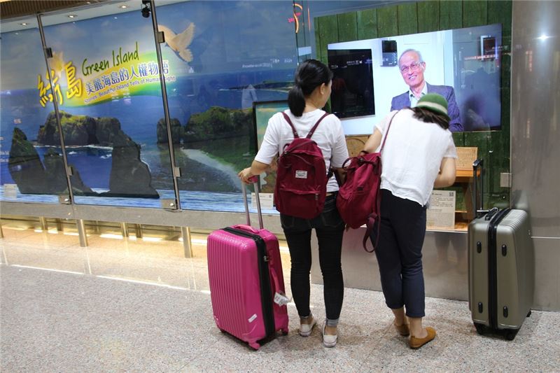 兩名香港遊客仔細觀看桃園國際機場文化櫥窗內講述的綠島人權文化園區白恐受難者故事