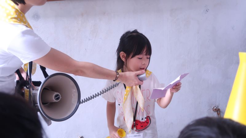 小小解說員打著黃色領巾、手拿大聲公,認真講述白色恐怖景美紀念園區的歷史