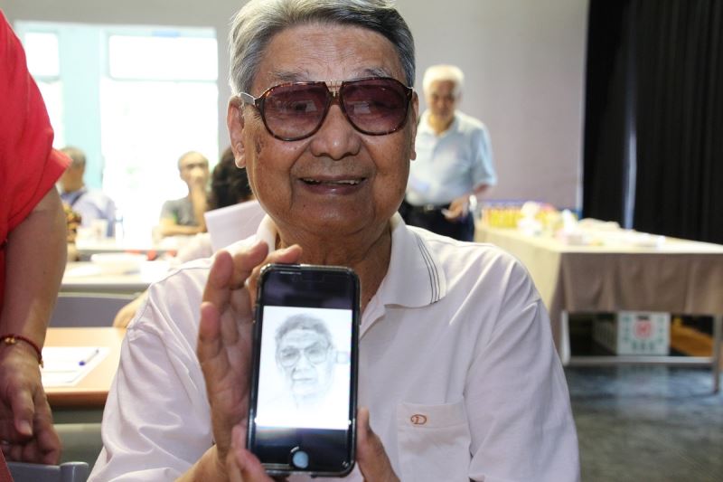 郭振純前輩開心展示手機中由年輕人為他手繪的素描肖像