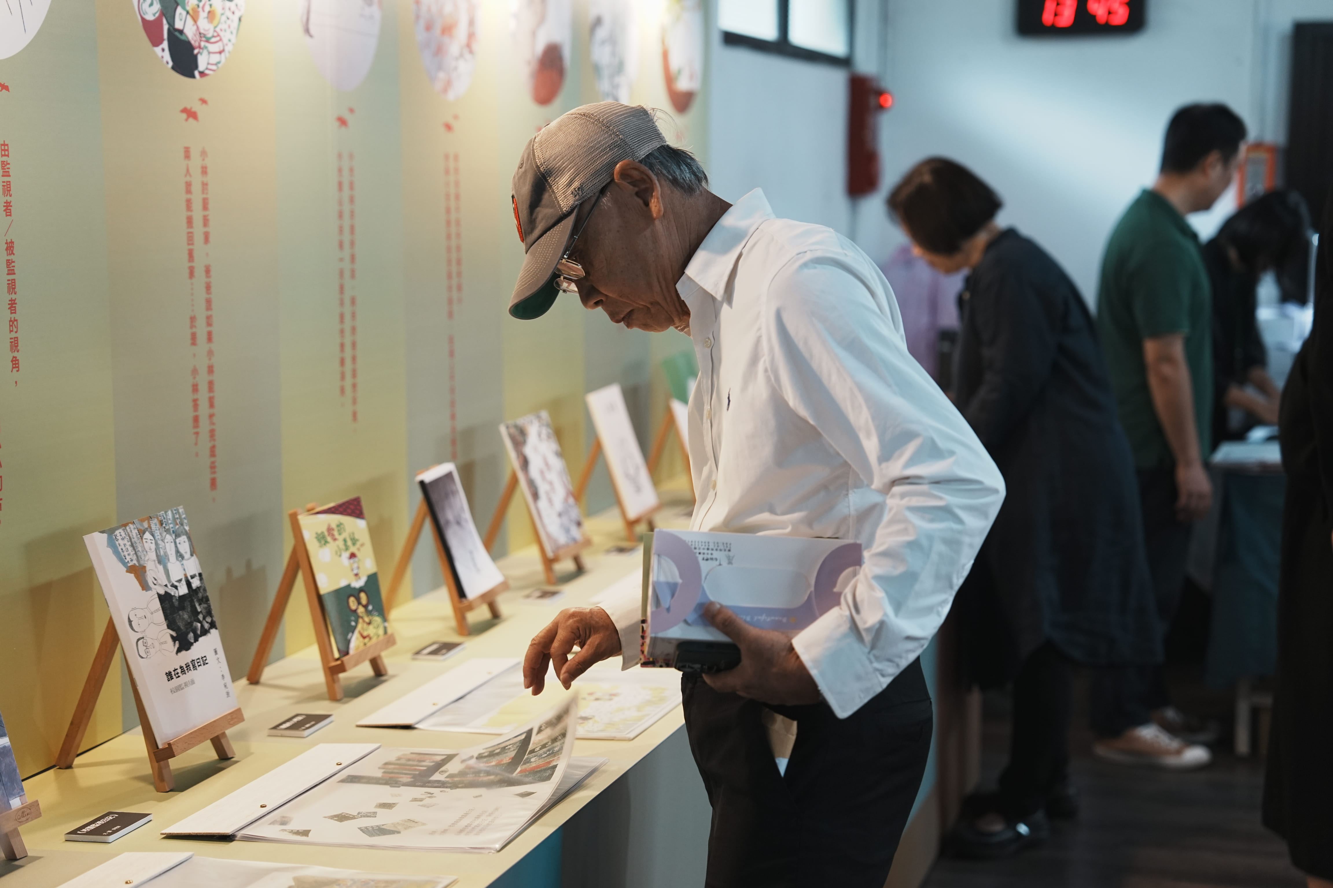 政治受難者前輩陳欽生於現場翻閱工作坊繪本成果。